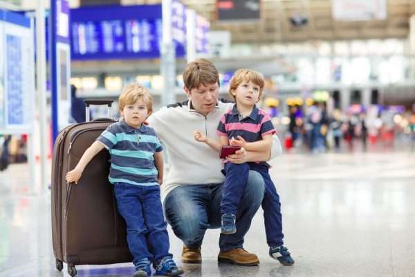 Мужчина с детьми и чемоданом в аэропорту