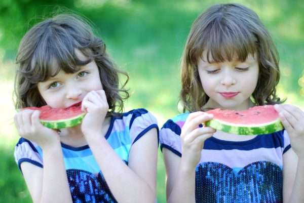 Девочки-близнецы едят арбуз