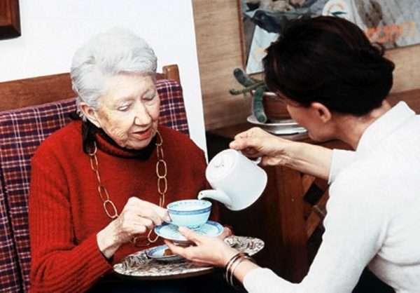 Пожилой женщине наливают чай