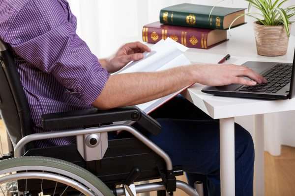 Мужчина на инвалидной коляске работает за компьютером